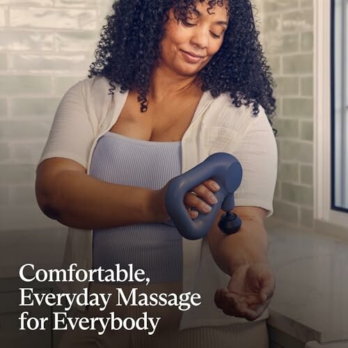 Woman using a handheld massage device on her arm.