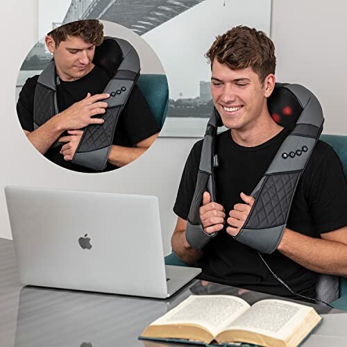 Man using a neck massager while sitting at a desk with a laptop and open book.