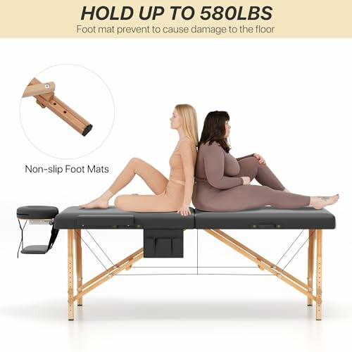 Two people sitting on a massage table demonstrating its weight capacity of up to 580 lbs.