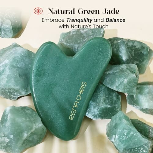 Natural green jade massage tool surrounded by raw jade stones.