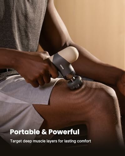 Person using a portable muscle massager on their leg.