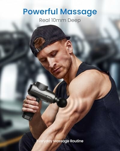 Man using a massage gun on his arm in a gym setting.