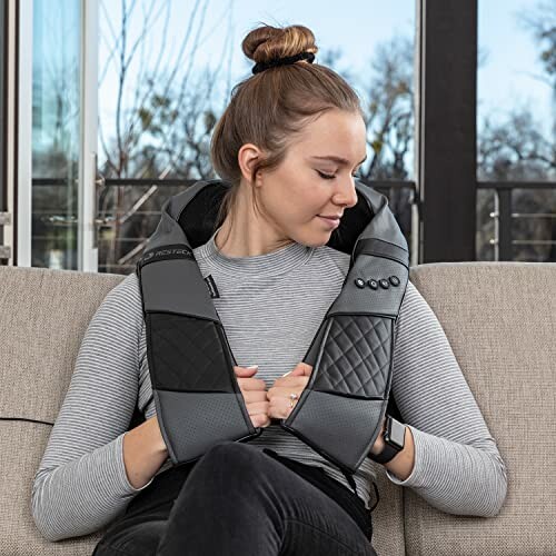 Woman using a neck massager on a couch